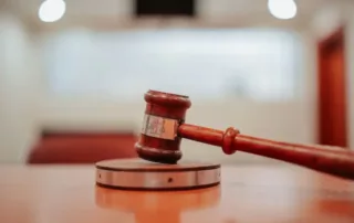 Image of a judge's gavel laying on it's stand, with a blurry background.
