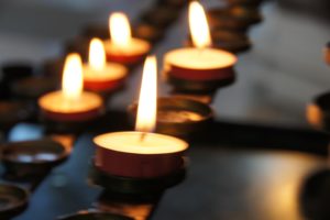 Image of a row of mourning candles lit, slightly out of focus.