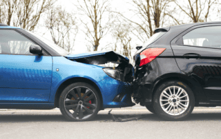 An image of two cars directly after a collision. A blue car rear-ended a black car, resulting in its hood being bent up.